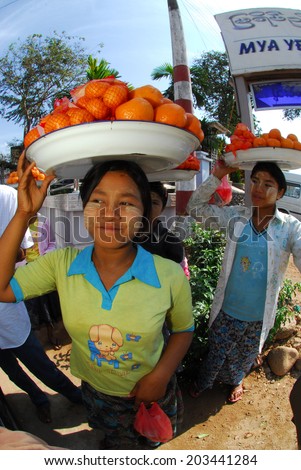 MANDALAY,MYANMAR- JANUARY 29 : An unidentified Burmese woman carrying the oranges on her head for sell at Mandalay, Myanmar on January 29,2014. carrying by head is Burmese traditional at myanmar .