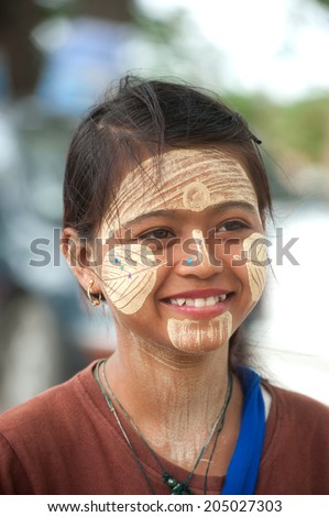 INWA,MYANMAR-JULY 1 : Young Myanmar woman with thanaka on her smile face is happiness on July 1,2014 in Inwa city,Middle of Myanmar.Thanaka is a yellowish-white cosmetic paste made from ground bark.