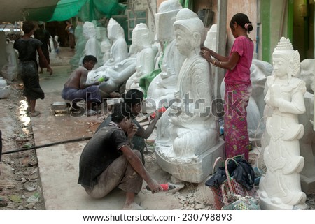 MANDALAY,MYANMAR-JUNE 29:On the grounds man and women polishing on the finishing touches of a Buddha sculpture. Although the most expensive are carved from marble on June 29,2014 in Mandalay,Myanmar.