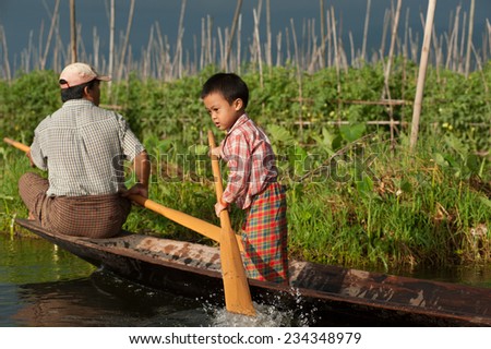 INLE,MYANMAR-SEPTEMBER 29 : Young boy is paddle by leg training on September 29,2014 at Inle Lake,Shan state in Myanmar.Intha monority people paddle with leg-rowing style unique the one in the World.