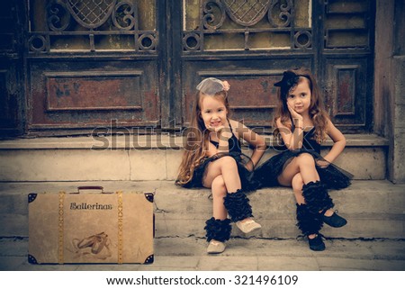 Two vintage little ballerinas in black tutu sitting on stairs