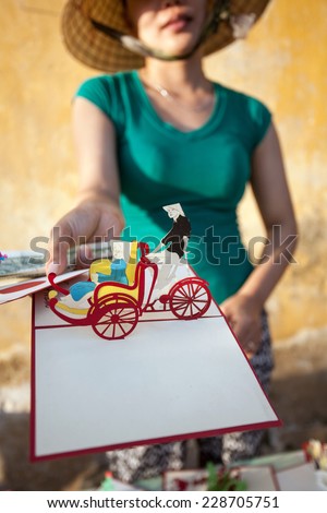 HOI AN, VIETNAM - OCTOBER 21: Unidentified vendor is selling pop-up wishing card souvenir for traveller on the street in old town at UNESCO World Heritage on Oct 21, 2014 in Hoi An, Vietnam.