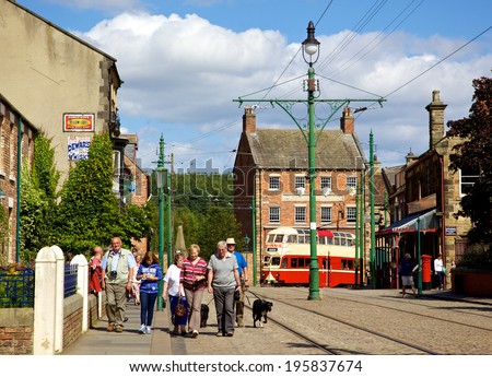 BEAMISH, UK - JULY 27, 2012: Tourists, tramlines and an old tram in the high street of the Edwardian town that forms part of Beamish Museum in County Durham, England.