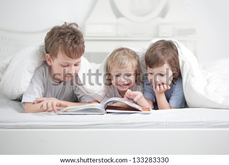 three boy read book indoors