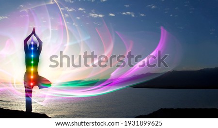 Silhouette of woman sits in a otus pose on beach sunset view, glowing seven all chakra. Kundalini energy. girl practicing yoga meditation outdoors