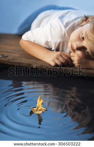 boy play with leaf ship in water (focus on ship)