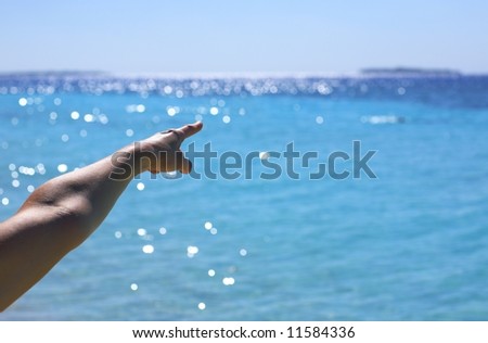 Woman\'s hand point to island in a ocean