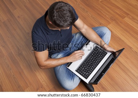 young man sitting on the floor working on laptop computer at home