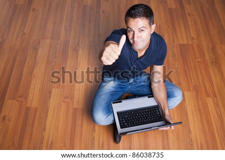 man sitting on the floor with laptop and with his thumb up