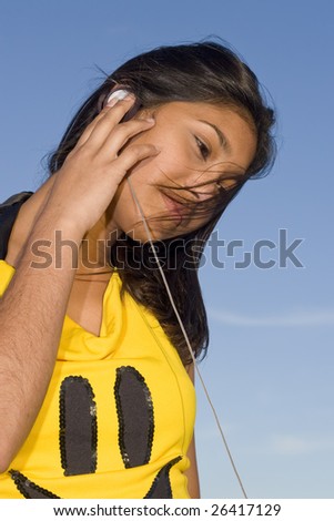Girl with smiley face top listening to music on headphones