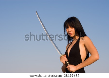Asian model posing with a Samurai sword against blue sky