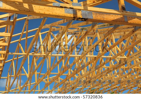 Wood Roof Trusses viewed from inside of new home looking out to a blue sky above