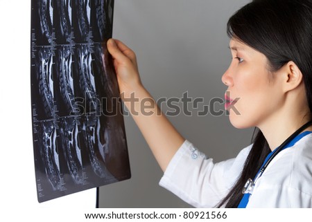 Attractive female Asian Doctor looking at MRI white lab jacket and stethoscope