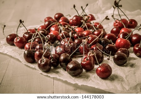fresh sour cherries in paper with water drops on grey wooden table