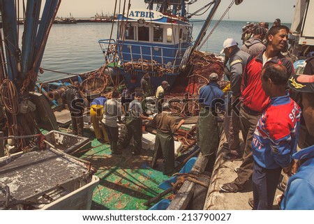 Daklha, Morocco, June 21, 2014: Daily Fish market in Daklha, Western Sahara, Morocco, were fresh seafood is sold everyday. Fishermen and their boat on the harbour. Vintage edition.