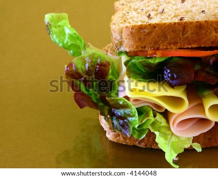 wholebread sandwich with ham and cheese on brown background