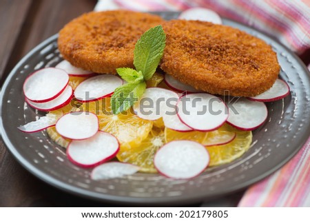 Close-up of roasted fish burgers with oranges and radish