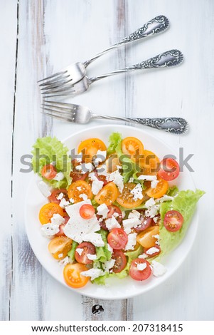 Salad with different types of tomatoes, cheese and salad leaves