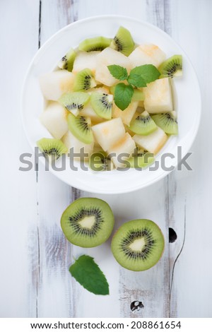 Melon and kiwi fruit salad on a glass plate, view from above