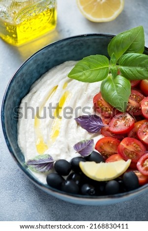 Greek tarama dip served in a blue bowl with olives, cherry tomatoes and fresh basil leaves, close-up, vertical shot Stok fotoğraf © 