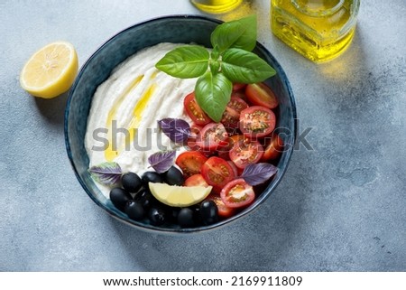 Bowl of greek tarama dip with black olives, cherry tomatoes and fresh basil, elevated view on a light-blue stone background, studio shot Stok fotoğraf © 