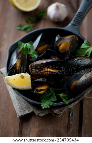 Boiled mussels with lemon, parsley and garlic, selective focus