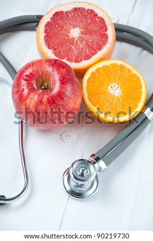 Healthy eating concept with stethoscope and fresh fruits on doctor\'s smock