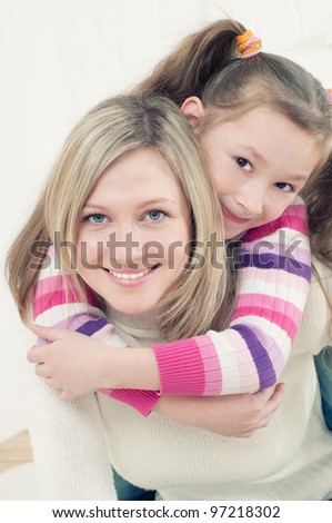 Carrying a generation: mother giving her little daughter a piggyback ride
