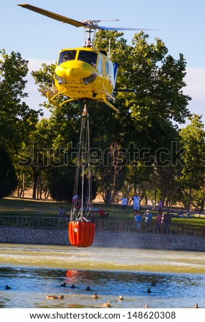 MADRID, SPAIN - AUGUST 3 : Fire rescue heavy helicopter with water bucket, goes to a fire in Madrid on August 3, 2013, Spain.