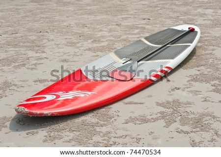 surfboard and oar on the sand at the beach