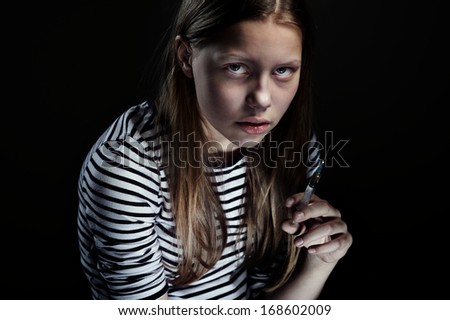 Dark portrait of a drug addicted teenager girl with syringe