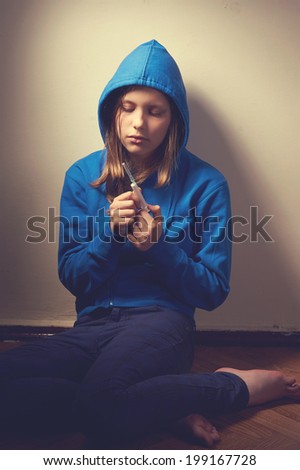 Dark portrait of a junk teen girl with syringe, problems with drugs