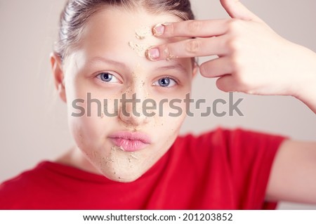 Happy teen girl with scrub mack on her face having fun and making funny faces