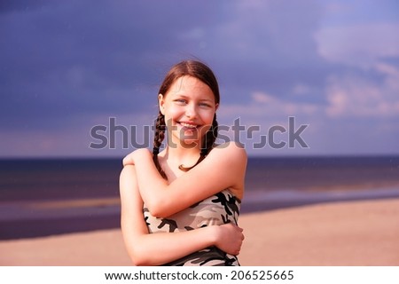 Cute happy teen gir staying on the beach and smiling