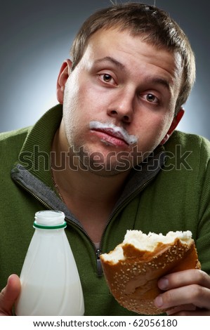 Portrait of funny man with bread and bottle. Yogurt traces on his lips