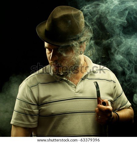 Dark fine art portrait of a smoking man in hat. With tobacco pipe.