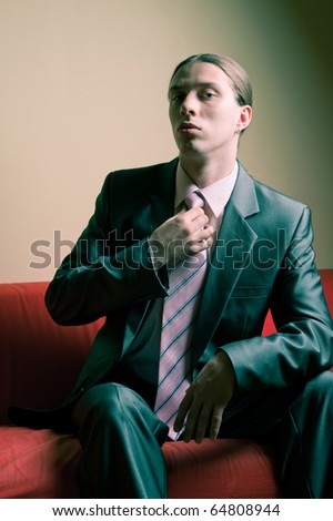 Portrait of longhaired serious man in suit sitting