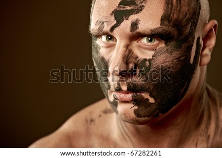 Emotional portrait of fighter. War paint on his face and body