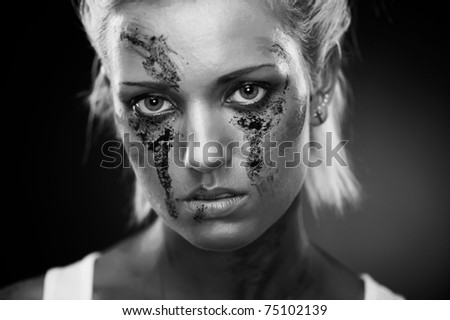 Depressed girl with dirt on her face, closeup. Studio shot.