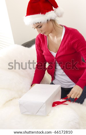 young woman prepares gift box to Christmas with red ribbon