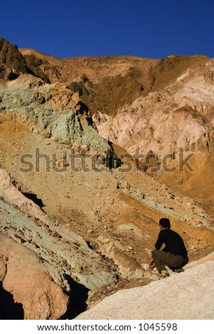 Young man looking at the beautiful colors in the Artists Palate at Death Valley National Park in California, USA.