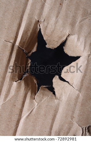 close-up of large hole in the brown paper (cardboard)