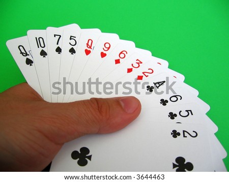 bridge playing - one hand (Q,10,7,5 spades, Q,9 hearts, 6,3,2 diamonds, A,6,5 clubs)  background green, selective focus,