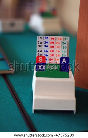 equipment to bridge playing: green tables, biding box,