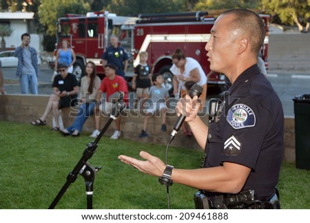 GLENDALE, CA - AUGUST 5, 2014: A police officer at a microphone discusses neighborhood crime prevention with community members at a National Night Out against crime community fair.