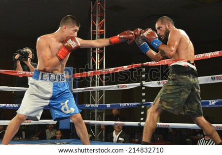 GLENDALE, CA - AUGUST 9, 2014: Boxer Luis Sedano extends his left arm,  at opponent Luis Diaz who braces defensively with gloves raised. The bout took place in Glendale, California on August 9, 2014.