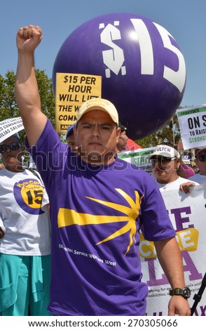 LOS ANGELES, CA   APRIL 15, 2015: A protestor raises his fist in the air during a rally advocating raising the minimum wage in Los Angeles on April 15, 2015.