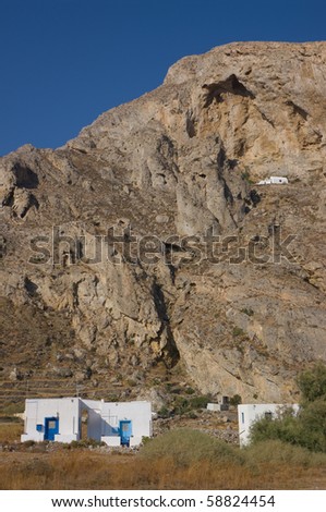 church built into a cliff face with shanty type homes below in the foreground