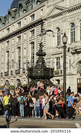 LONDON, ENGLAND - JUNE 21, 2014: Crowds, mostly of tourists, enjoying the sunshine at the Shaftesbury Memorial, known as Eros, in Piccadilly Circus, London.