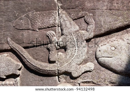Ancient Khmer bas relief carving showing a crocodile catching a fish in the Tonle Sap lake.  Bayon Temple, Angkor Thom, Siem Reap, Cambodia.
